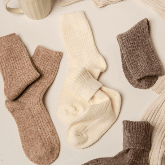 Bed&Butter Cream wool blend socks laid flat between light choccy and light brown socks, showing ribbed look, in a cosy and comfy setting.